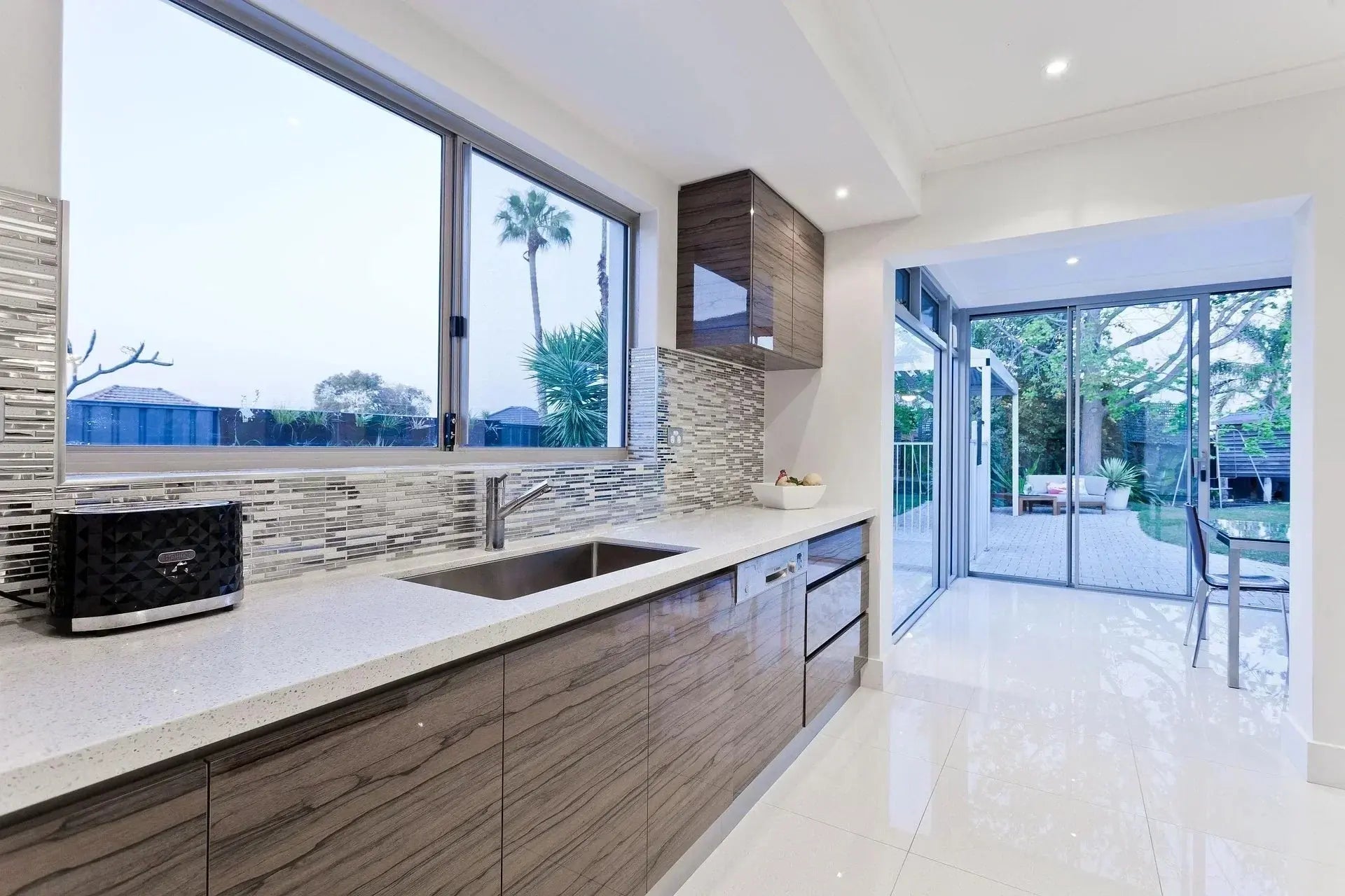A modern kitchen featuring a large window, a sink, and a Riobel faucet, showcasing a bright and functional design
