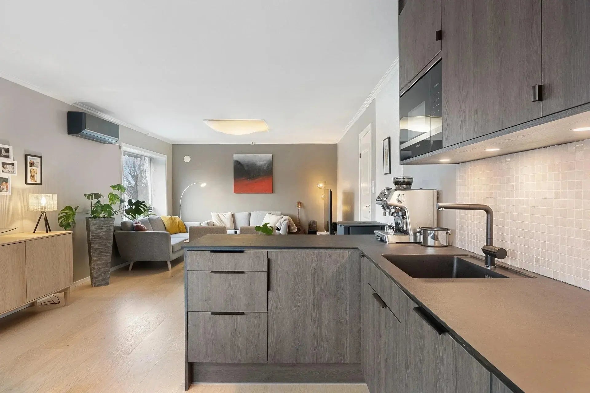 A modern kitchen featuring wooden floors, gray cabinets, and stylish bosco sinks for a contemporary look