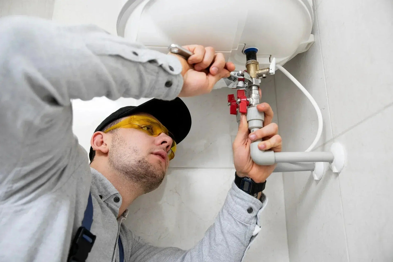 A contractor in a hard hat repairs a pipe at the Contractors Centre, showcasing skilled workmanship and safety practices.
