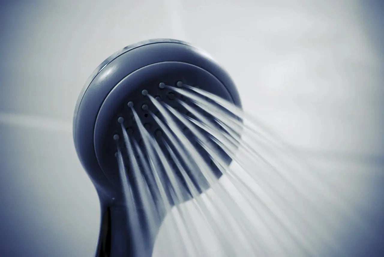 A close-up view of a shower head with water cascading down in a clear, refreshing stream.