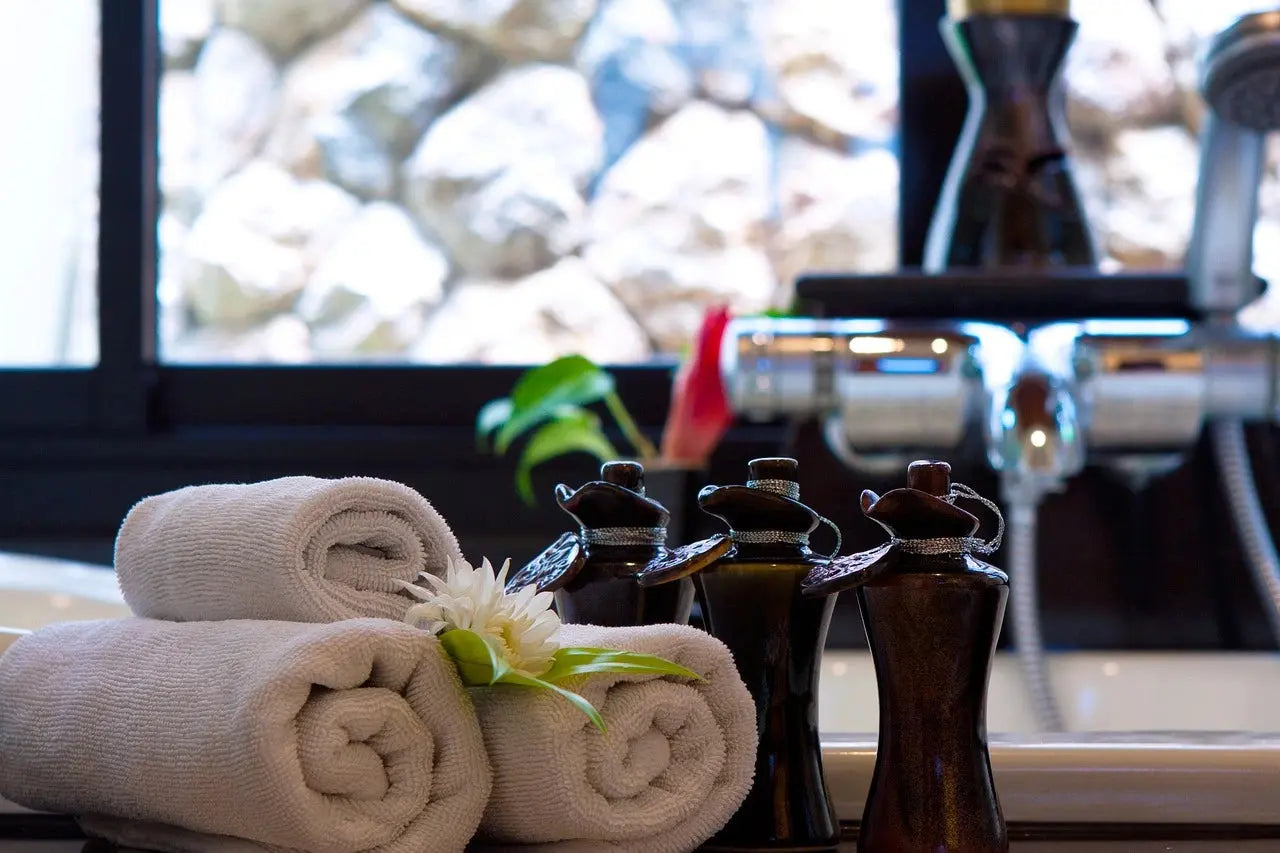 A well-appointed bathroom featuring a sink, neatly arranged towels, and a decorative flower for a touch of elegance.
